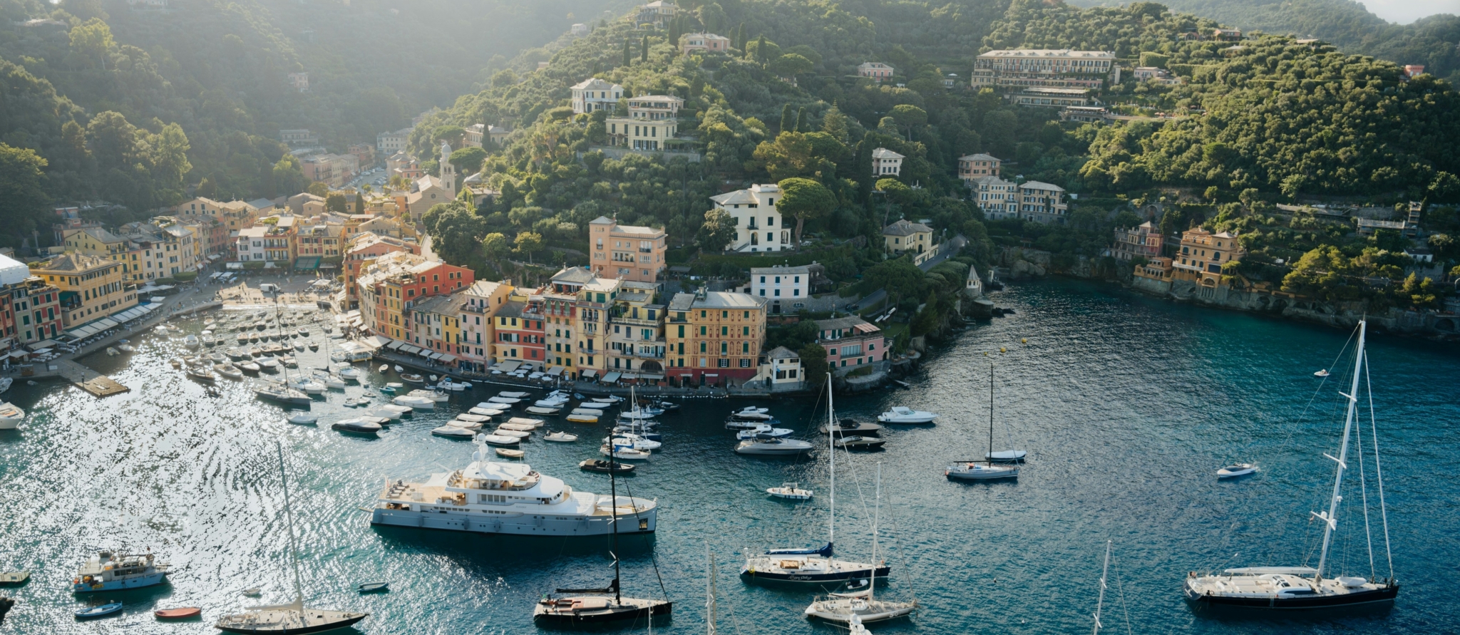 Haven van Portofino met kleurrijke huizen, jachten en groene heuvels aan de Italiaanse kust.