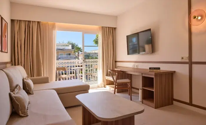 Lichte woonkamer van een One Bedroom Suite in Zafiro Can Picafort met comfortabele bank en balkon.