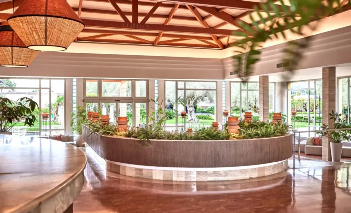 Ruime en lichte hotellobby van Zafiro Can Picafort met moderne inrichting, houten balken en uitzicht op de tuin.