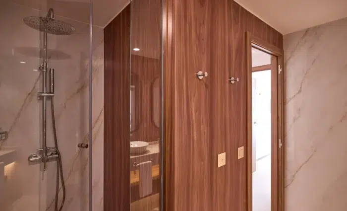 Luxe badkamer van Zafiro Can Picafort met ruime regendouche, glazen douchewand en marmerlook tegels.